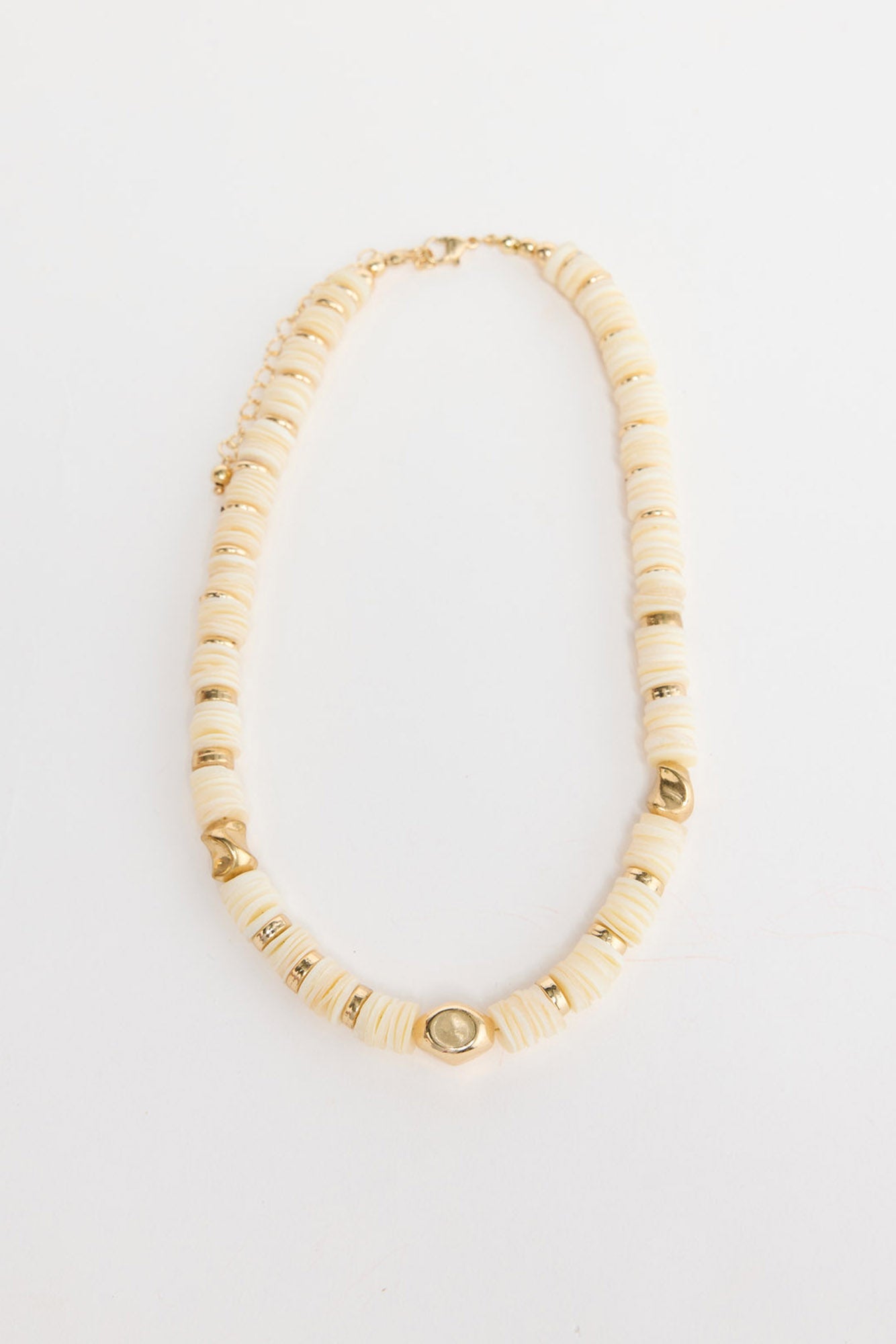 Cassian beaded necklace laid flat, showing cream disc beads interspersed with polished gold-tone accent beads