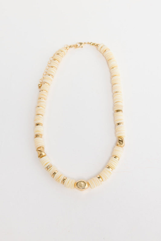 Cassian beaded necklace laid flat, showing cream disc beads interspersed with polished gold-tone accent beads
