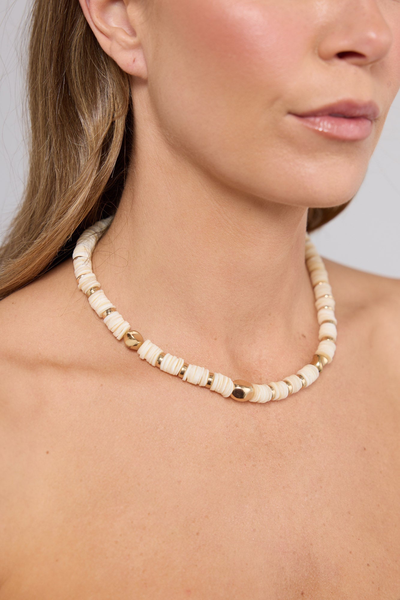 Close-up of the Cassian Necklace in Cream worn at the neckline, showing the disc bead texture