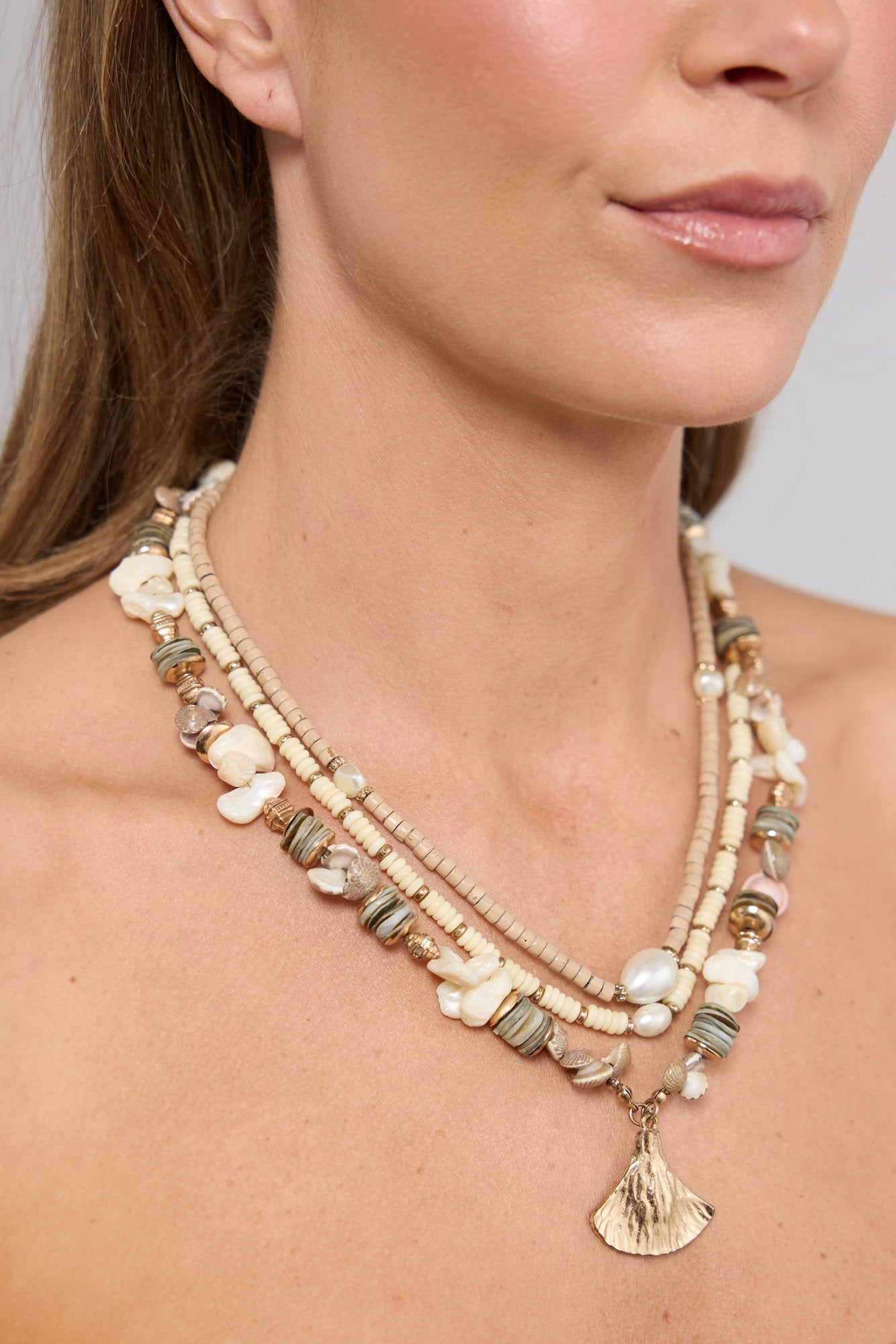 Close-up of the Otis Necklace in Cream worn at the neckline, showing the layered strands and fan pendant