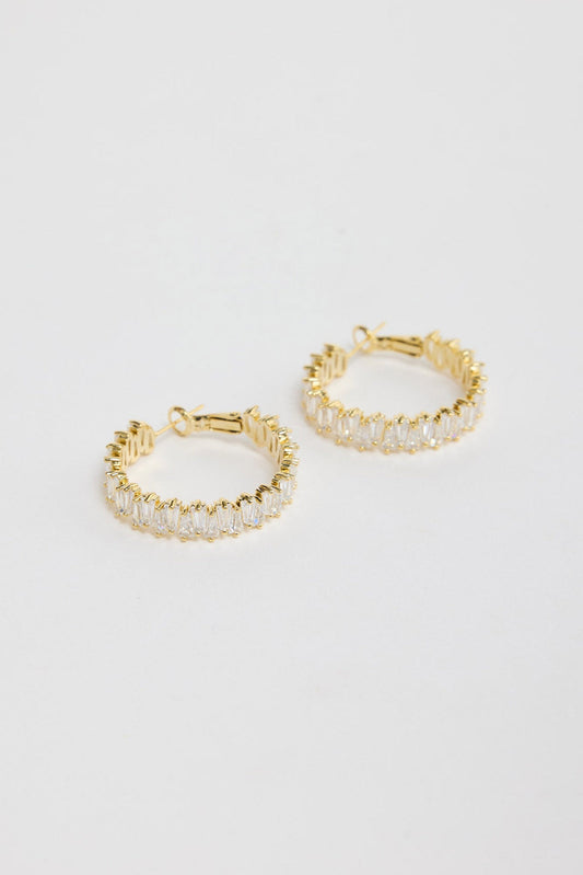 Oasis Earrings in Gold – gold-tone hoop earrings fully set with sparkling baguette crystals, shown flat on a white background.
