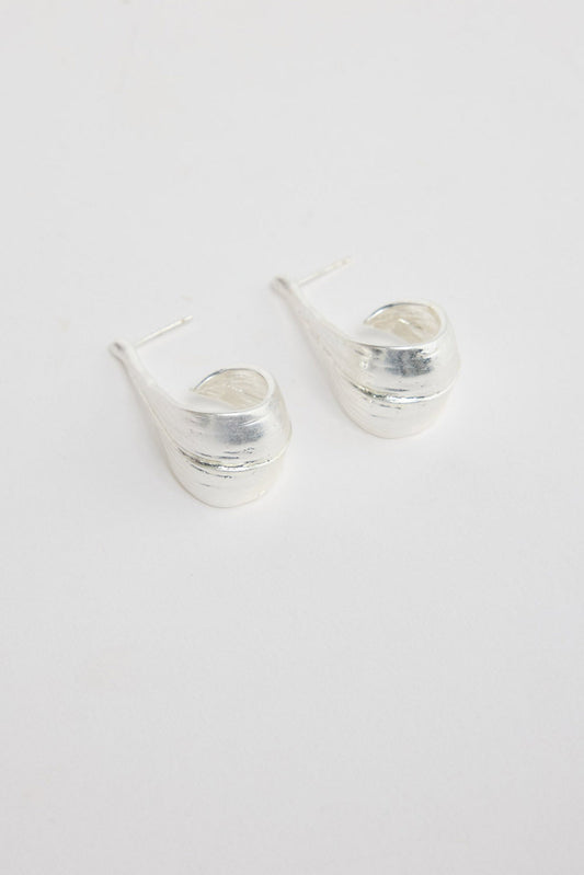 Lagoona Earrings in Silver – sculptural curved silver-tone teardrop earrings shown flat on a white background.